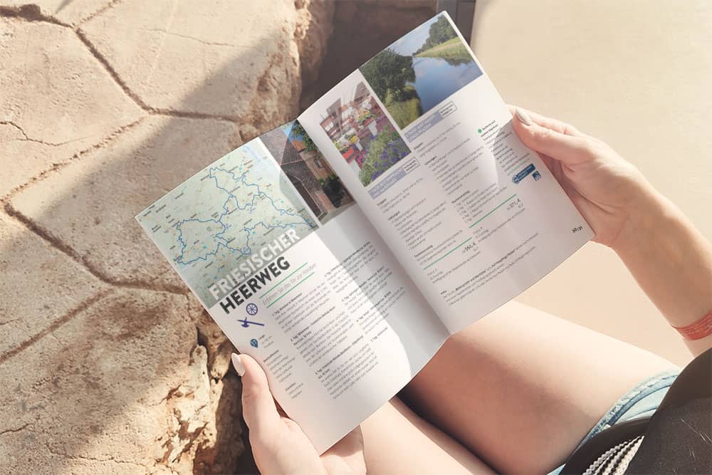 Man sieht die Hände einer Person die den Radkatalog der Ostriesland Tourismus GmbH hält.