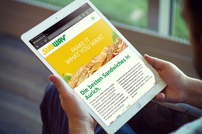 Man sieht ein Tablet auf dessen Bildschirm die Webseite von Subway abgebildet ist